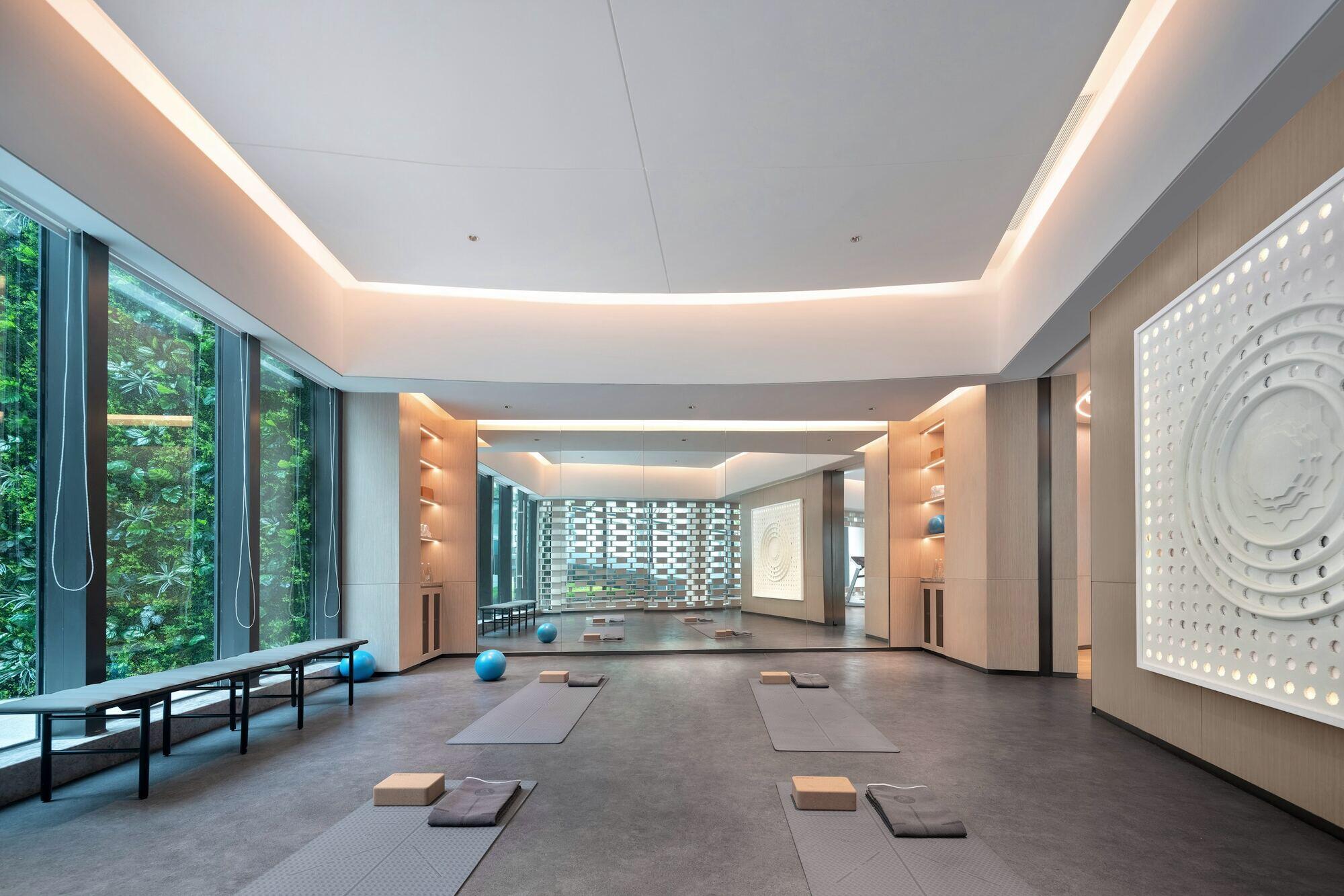 A bright studio with mats, blocks and exercise balls laid out on the floor, with large windows on the left